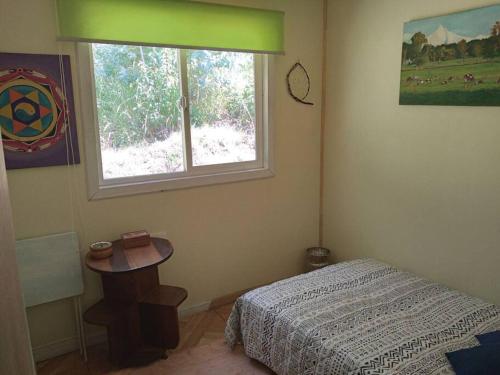 Schlafzimmer mit einem Bett, einem Tisch und einem Fenster in der Unterkunft Donde La Euli. in Pitrufquén