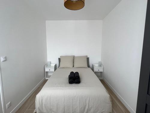 une chambre avec un lit avec deux chaussures dessus dans l'établissement Appartement contemporain et lumineux, à Aubervilliers