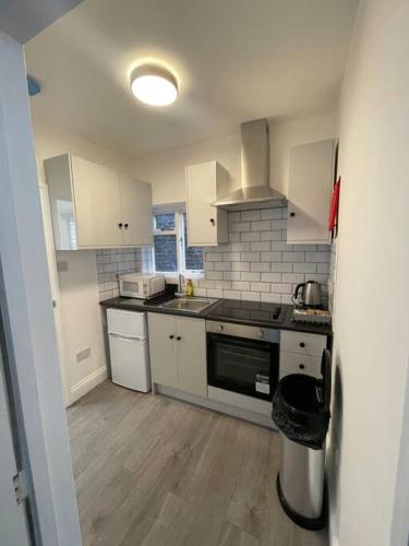 a kitchen with white cabinets and a stove top oven at Pearl- Deluxe London Studio Flat in South Norwood