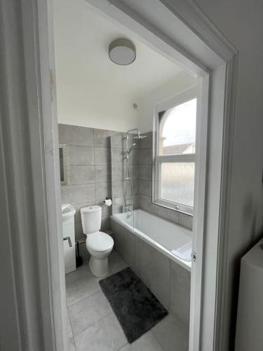 a bathroom with a toilet and a tub and a sink at Pearl- Deluxe London Studio Flat in South Norwood