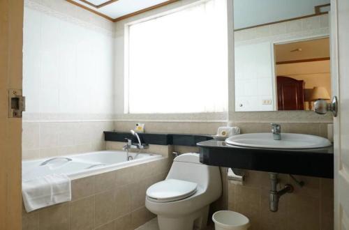 La salle de bains est pourvue de toilettes, d'un lavabo et d'un miroir. dans l'établissement 12PM Bangkok, à Bang Kapi