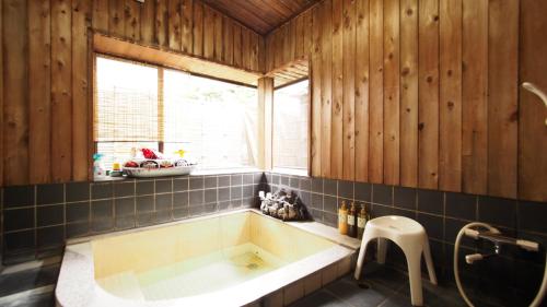 a large bath tub in a room with a window at お湯掛け流し『草津温泉湯畑』徒歩圏内※温泉街を大勢で遊びたい & 癒されたい in Kusatsu