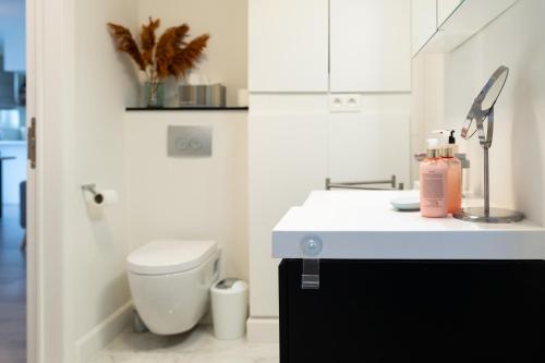 a white bathroom with a toilet and a sink at Heights of Kortrijk in Kortrijk