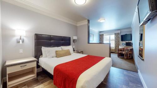 a bedroom with a large bed with a red blanket at Auberge l'Ambassadeur in Amqui