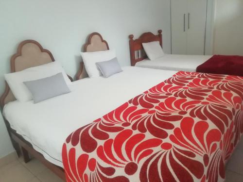 two beds with red and white covers in a room at Gold Reef Hideout in Johannesburg