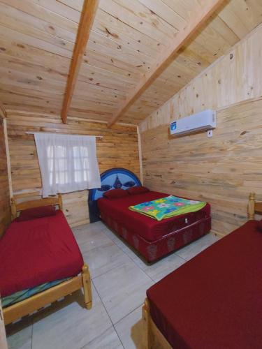 una camera con due letti in una cabina di legno di CABAÑA DOÑA ANGELA 