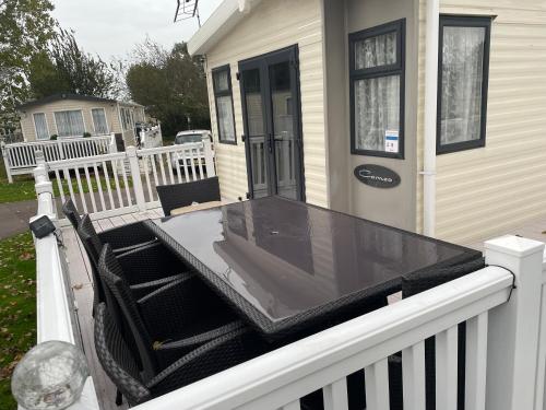 a screened in porch of a house with a table at Highfield Grange Caravan Park (Parkdean) in Little Clacton