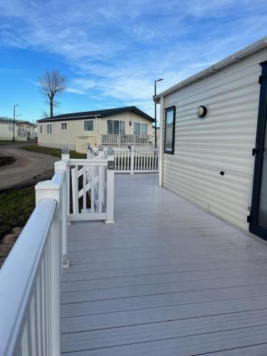 a wooden deck next to a white building at Highfield Grange Caravan Park (Parkdean) in Little Clacton