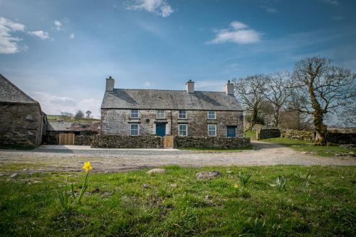 an old stone house with a field in front of it at Cwmain in Cerrigydrudion