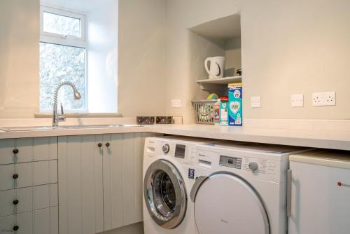 a kitchen with a washing machine and a sink at Cwmain in Cerrigydrudion
