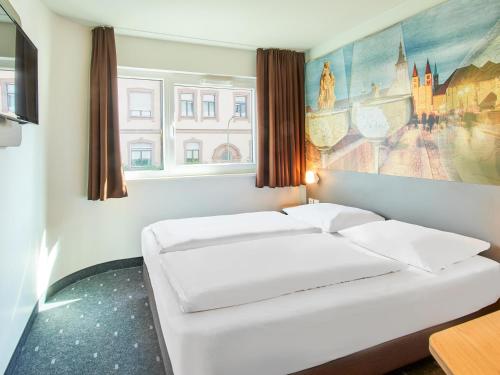 ヴュルツブルクにあるB&B Hotel Würzburgの壁に絵画が飾られた部屋のベッド2台