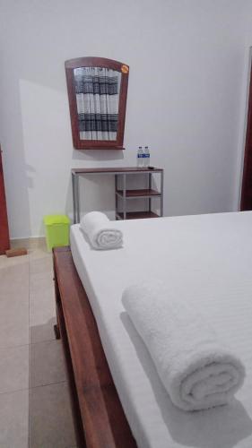 a bedroom with a bed with white sheets and towels at Kandy River Garden in Kandy