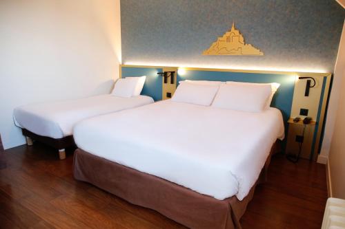 two beds in a hotel room with white sheets at Hôtel de France Vire in Vire