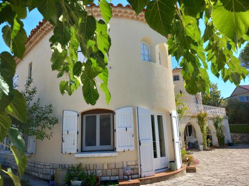 a house with white walls and windows and green leaves at le relais fleuri in Alès
