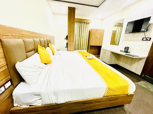 a bedroom with a large bed with yellow pillows at Hotel Superhouse by Wisdom Madhav in Mathura