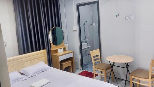 1 dormitorio con cama, espejo y mesa en Hà Linh Motel, en Vung Tau