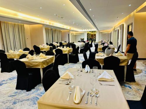 a restaurant with tables and chairs and a man standing in the middle at Wescott Plaza Hotel Apartments LLC Formerly West Zone Plaza Hotel Apts in Dubai