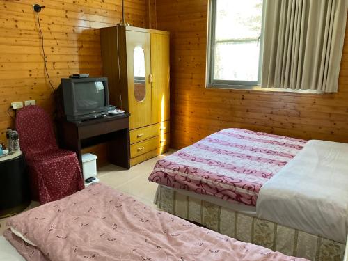 a bedroom with two beds and a tv and a chair at 星光山悦景觀民宿 in Heping