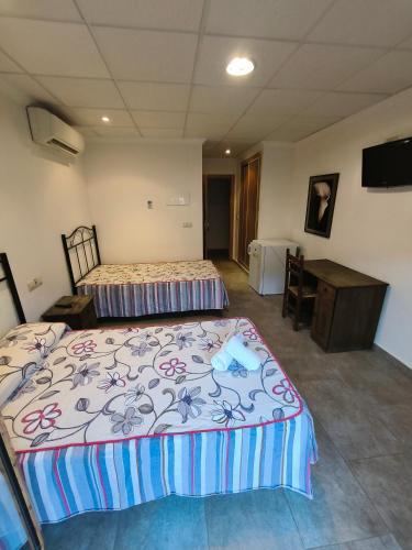 a bedroom with two beds and a desk and a television at Ca' La Conchin in Cortez de Pallas