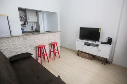 a living room with two red stools and a television at Refúgio em Copa in Rio de Janeiro