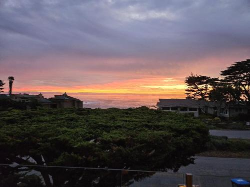 a sunset over the ocean with houses and trees at 4812 Windsor Bl. in Cambria