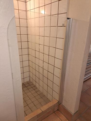a shower in a bathroom with white tile at Litet strandnära hus på Adelsö in Adelsö