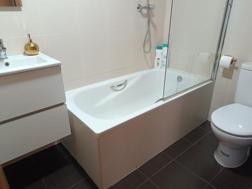 a bathroom with a tub and a toilet and a sink at Lujoso apartamento en Oliva in Oliva