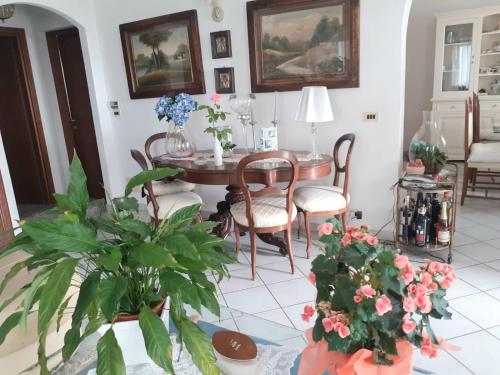 a living room with a table and chairs and flowers at La Maison des Rèves -Langhe Piemonte in Torre Bormida