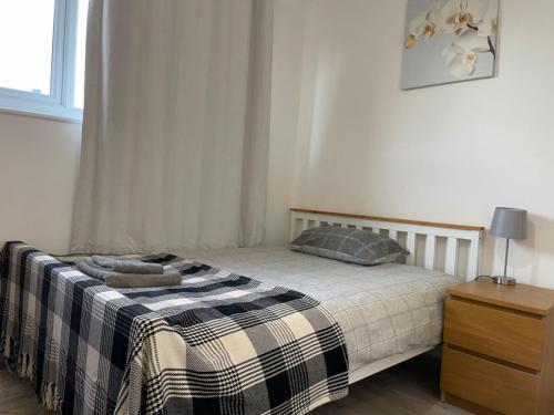 a bedroom with a bed with a plaid blanket at Double bedroom with bathroom en suite in London Docklands Canary Wharf E14 in London