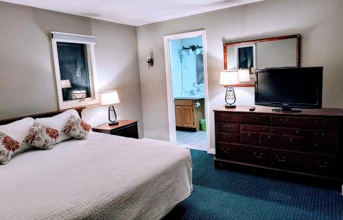 a bedroom with a bed and a flat screen tv at Stowe Motel & Snowdrift in Stowe