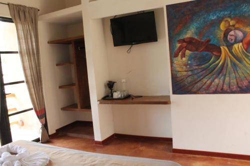 a bedroom with a painting and a tv on the wall at Axkan Palenque in Palenque