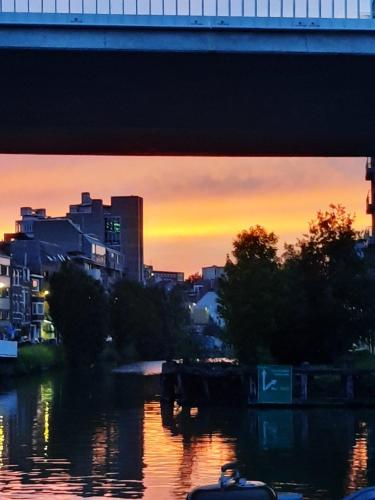 a bridge over a river with a city at sunset at Boat & Breakfast Bellevue in Ghent