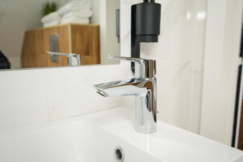 Un lavabo de baño con grifo y espejo. en Forest Boutique, en Piteşti