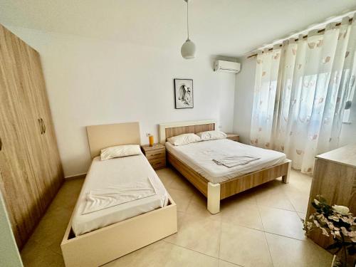 1 dormitorio con 2 camas y ventana en Villa Arberia en Durrës