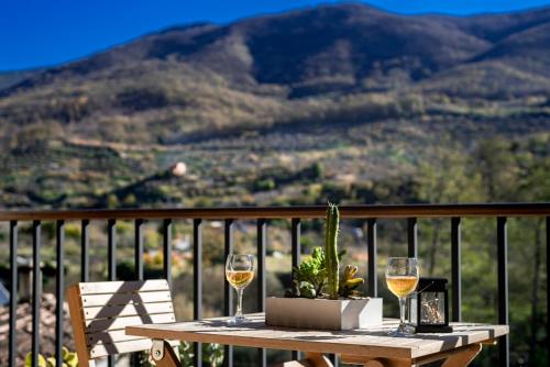 a table with two glasses of wine on a balcony at Casa Rural La Chopera del Jerte in Jerte