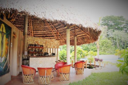 an outdoor bar with chairs and a straw umbrella at AXKAN PALENQUE, ALBERCAS, GASTRONOMIA MAR y TIERRA & TRAVEL AGENCY in Palenque