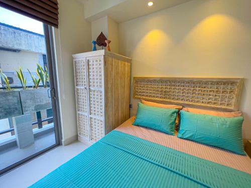 a bedroom with a bed with blue pillows and a window at Modern apartment in Colombo in Colombo