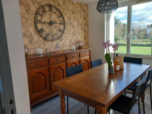 une table à manger avec une grande horloge sur le mur dans l'établissement Gite de la Belle Vie, à Noyers-sur-Cher