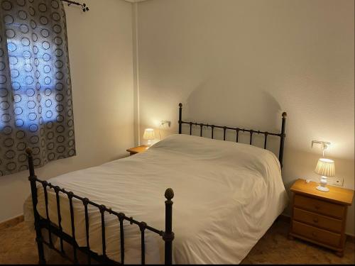 a bedroom with a bed with white sheets and a window at VILLA MARIA in Los Alcázares