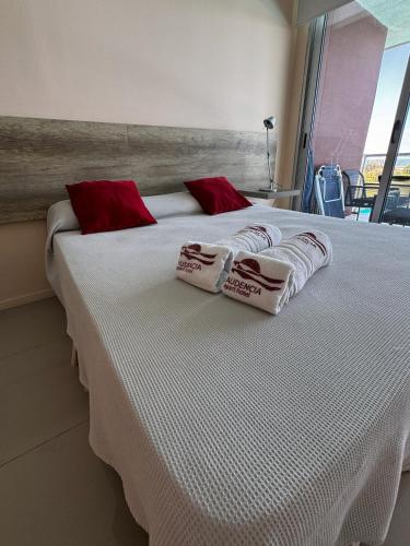 Una cama grande con almohadas rojas y blancas. en Audencia del Mar, en La Paloma