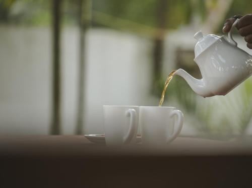 a person is pouring coffee into a tea cup at Marari Bobans villa in Mararikulam