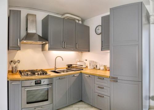 a kitchen with gray cabinets and a sink at Ballatoio Apartment by the Lake in Lesa