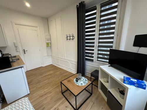 Elle comprend un petit salon avec une table et une télévision. dans l'établissement A la broche - 293, à Rouen
