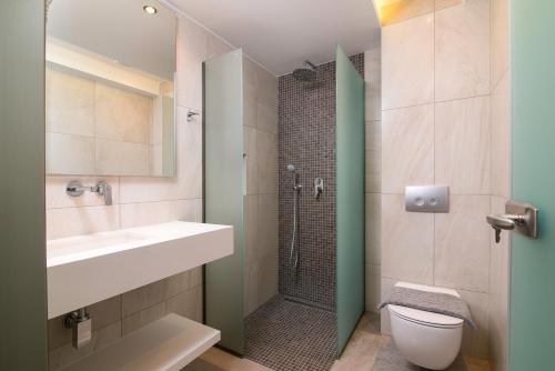 a bathroom with a shower and a sink and a toilet at Aegean Infinity Deluxe in Limenaria