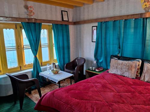 a bedroom with a red bed and a table with chairs at Conifer view guest house in Tangmarg