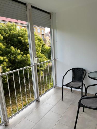a balcony with two chairs and a table and a window at Kelemen Apartman Nagykanizsa in Nagykanizsa
