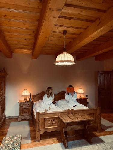 a man sitting in a bed in a room with wooden ceilings at Öreg Prés Butikhotel in Mór