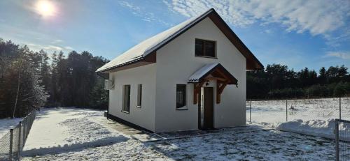 a small white house in the snow with a fence at Jaskółka Roztocze in Tomaszów Lubelski