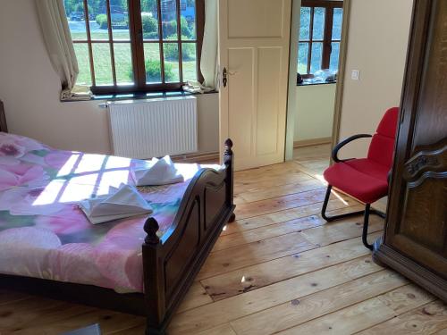 um quarto com uma cama e uma cadeira vermelha em Auberge au pont de Villettes em Lierneux