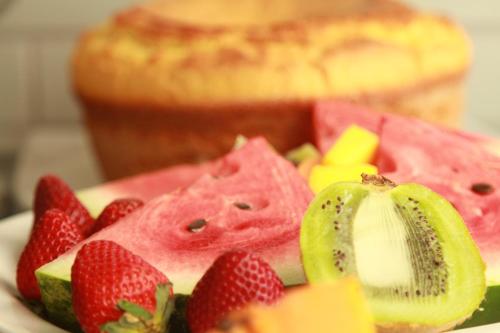 a plate of fruit with strawberries and kiwis and bread at Hotel Confiance Batel in Curitiba